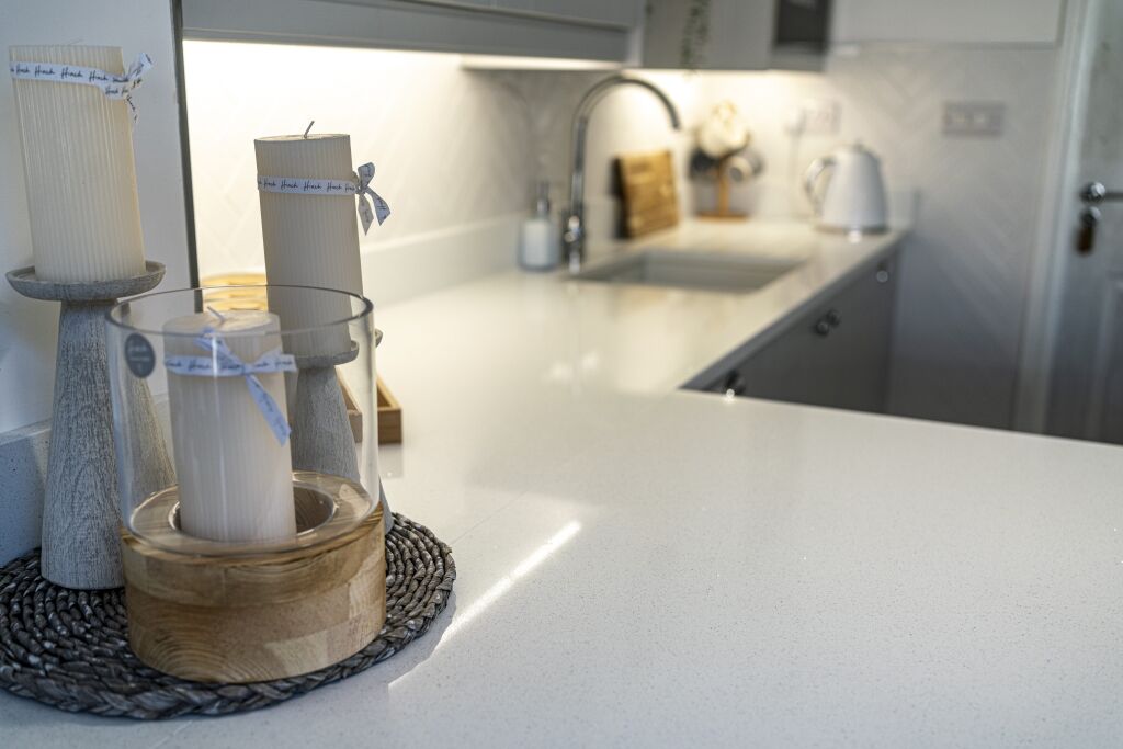 Close up view of Aspen Shimmer Quartz worktops beside the sink with soft lighting
