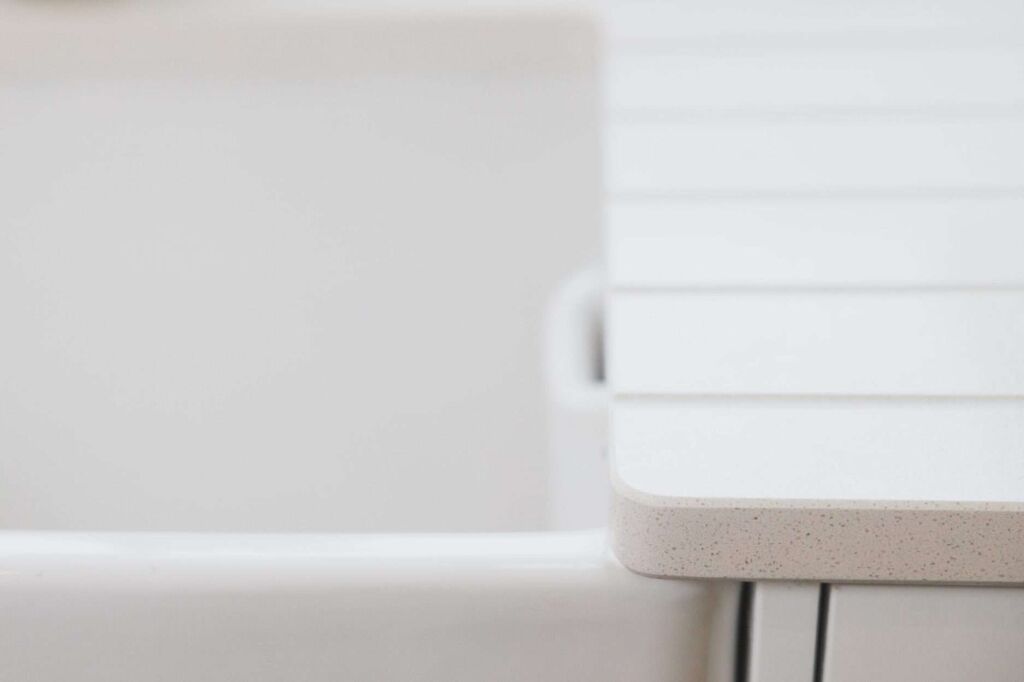 Close-up of Ice White Quartz worktop edge beside a sink, showing a smooth rounded corner and bright finish
