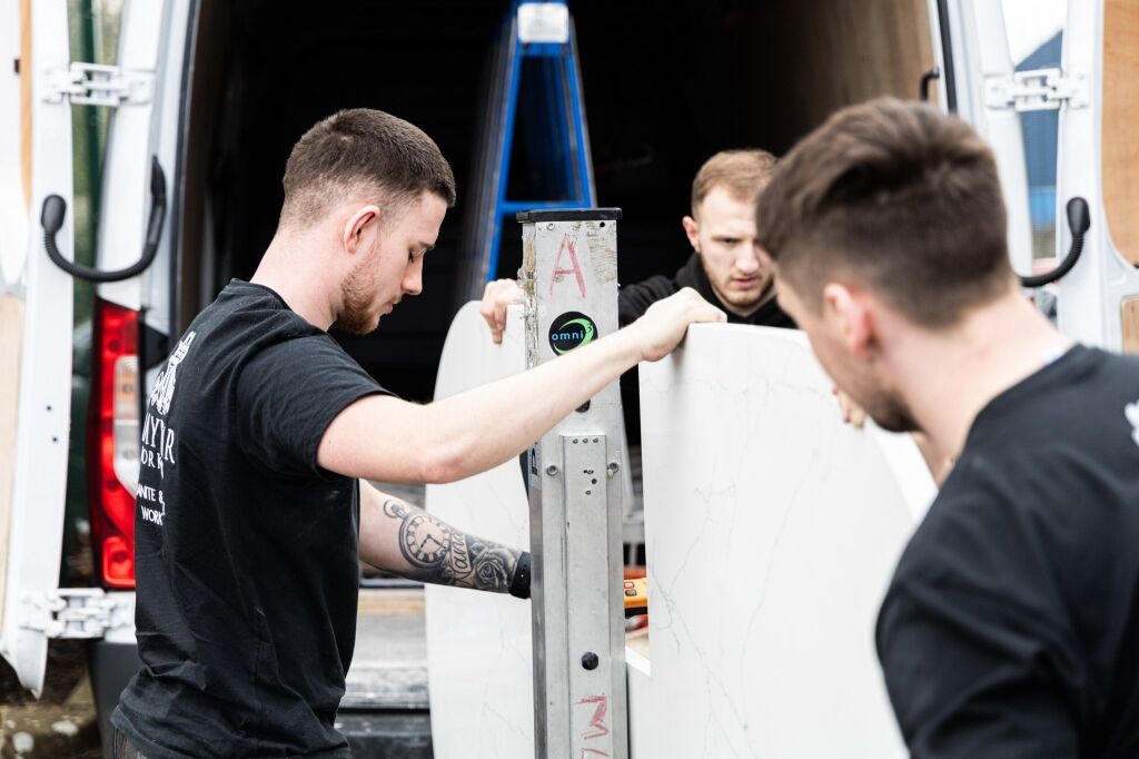 Mayfair Worktops Stonemasons handling a White Macaubus Quartz worktop slab during fitting preparation