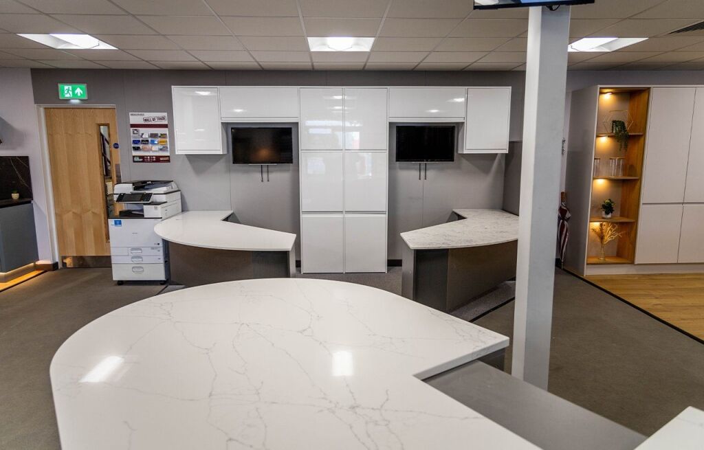 Benchmarx Witney showroom display featuring White Macaubus Quartz worktops with curved edges and a smooth white finish