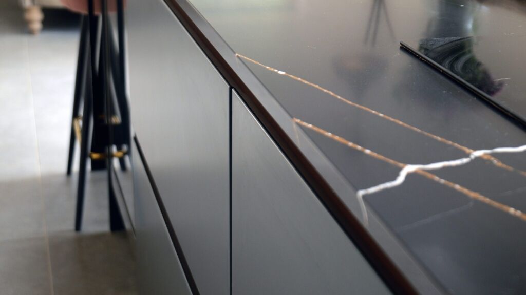 Sahara Noir Quartz worktop edge close-up showing polished black surface with gold-toned veining and a bold white vein near the front edge