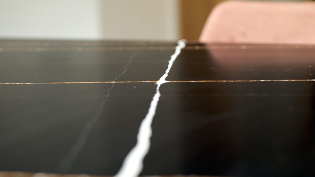 Sahara Noir Quartz close-up showing a bold white vein running across a polished black surface with fine gold-toned lines