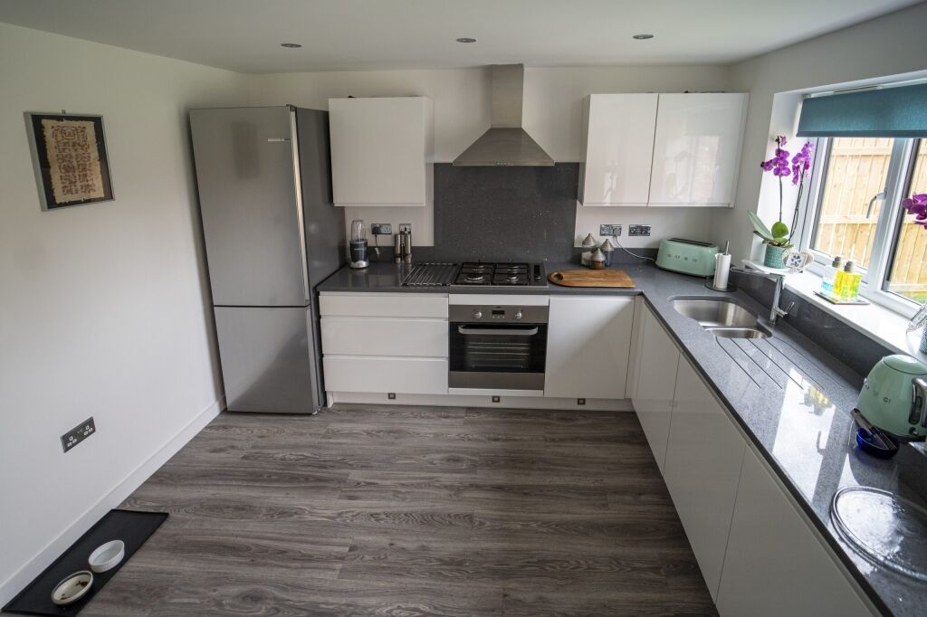 Modern kitchen with grey speckled Quartz worktops fitted to an L-shaped run and hob area