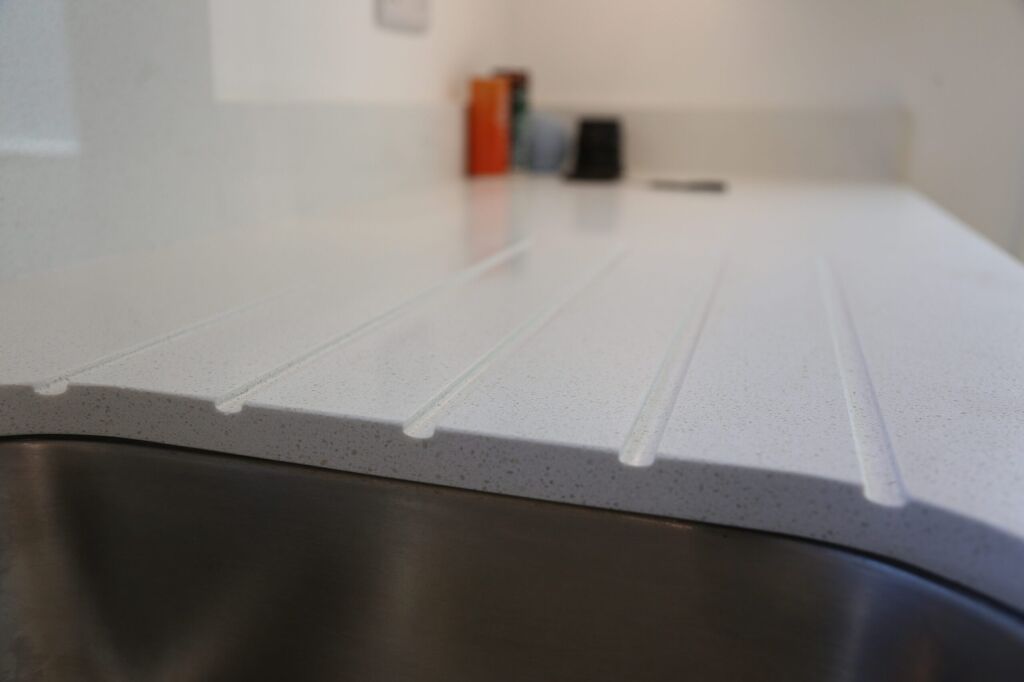 Close-up of Dover White Quartz drainer grooves showing clean channel lines and a smooth white finish