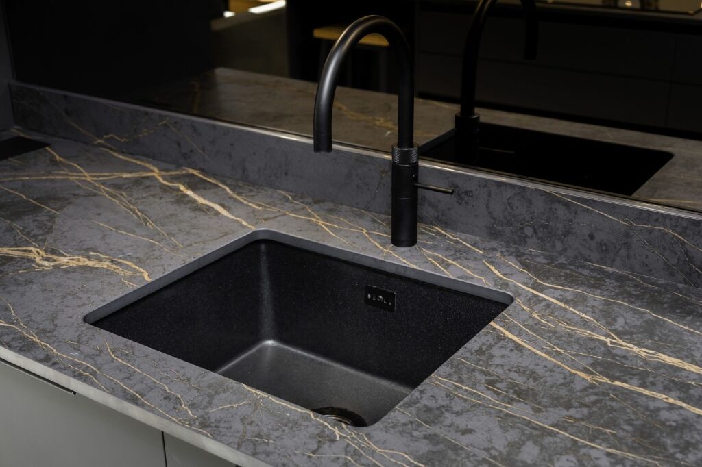 Laurent Porcelain worktop close-up showing an undermount black sink and black tap with gold veining through the surface.