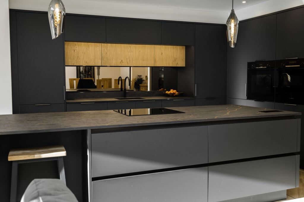 Laurent Porcelain worktop installed along a modern sink run with black tap, undermount sink and warm wood splashback.