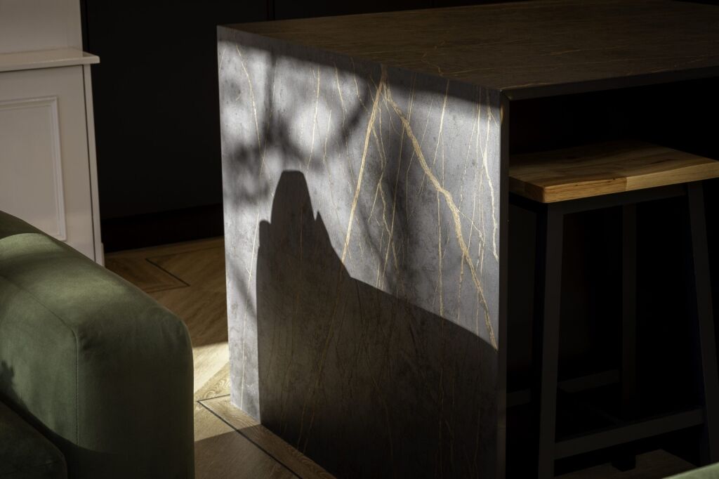 Laurent Porcelain waterfall end panel detail showing gold veining on a dark porcelain surface beside cabinetry.