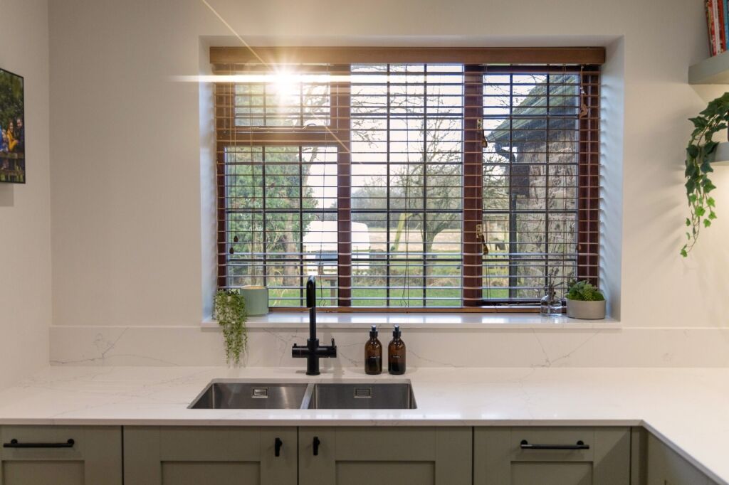 White Macaubus Quartz sink run with an undermount sink and black tap, shown beneath a large window