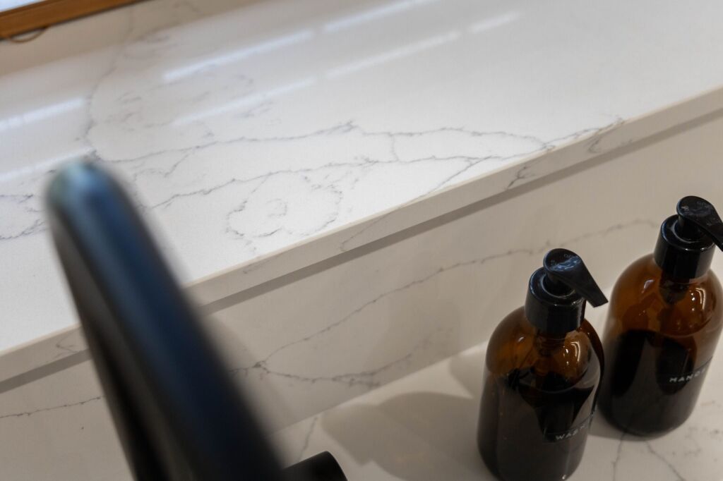 White Macaubus Quartz worktop close-up showing subtle veining and a clean edge beside kitchen bottles