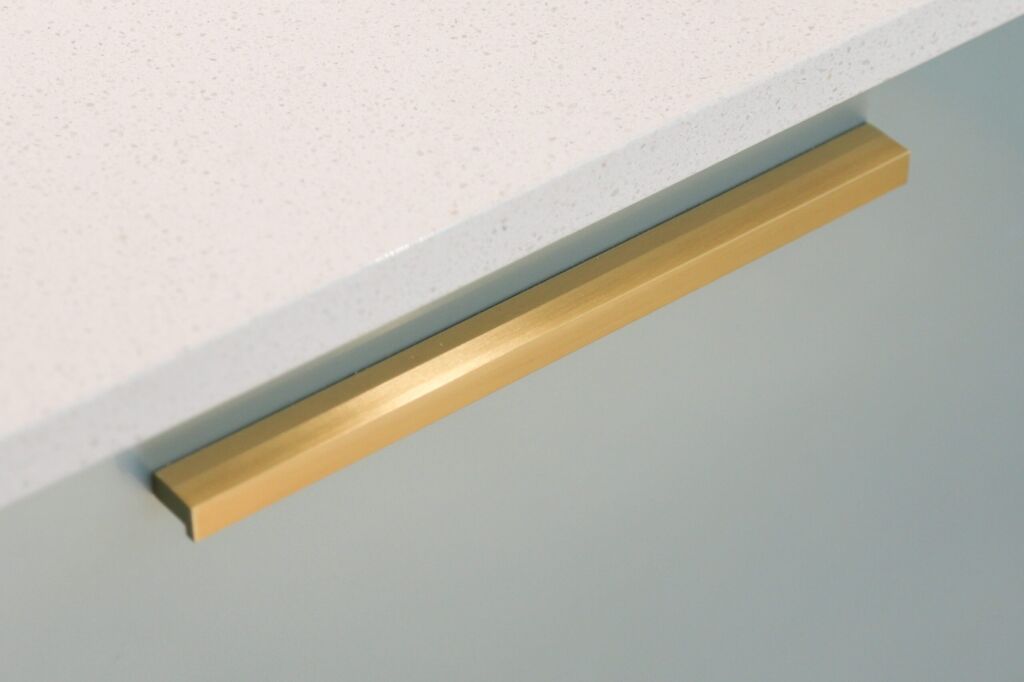 Dover White Quartz worktop edge close-up above pale green cabinetry showing a smooth white finish