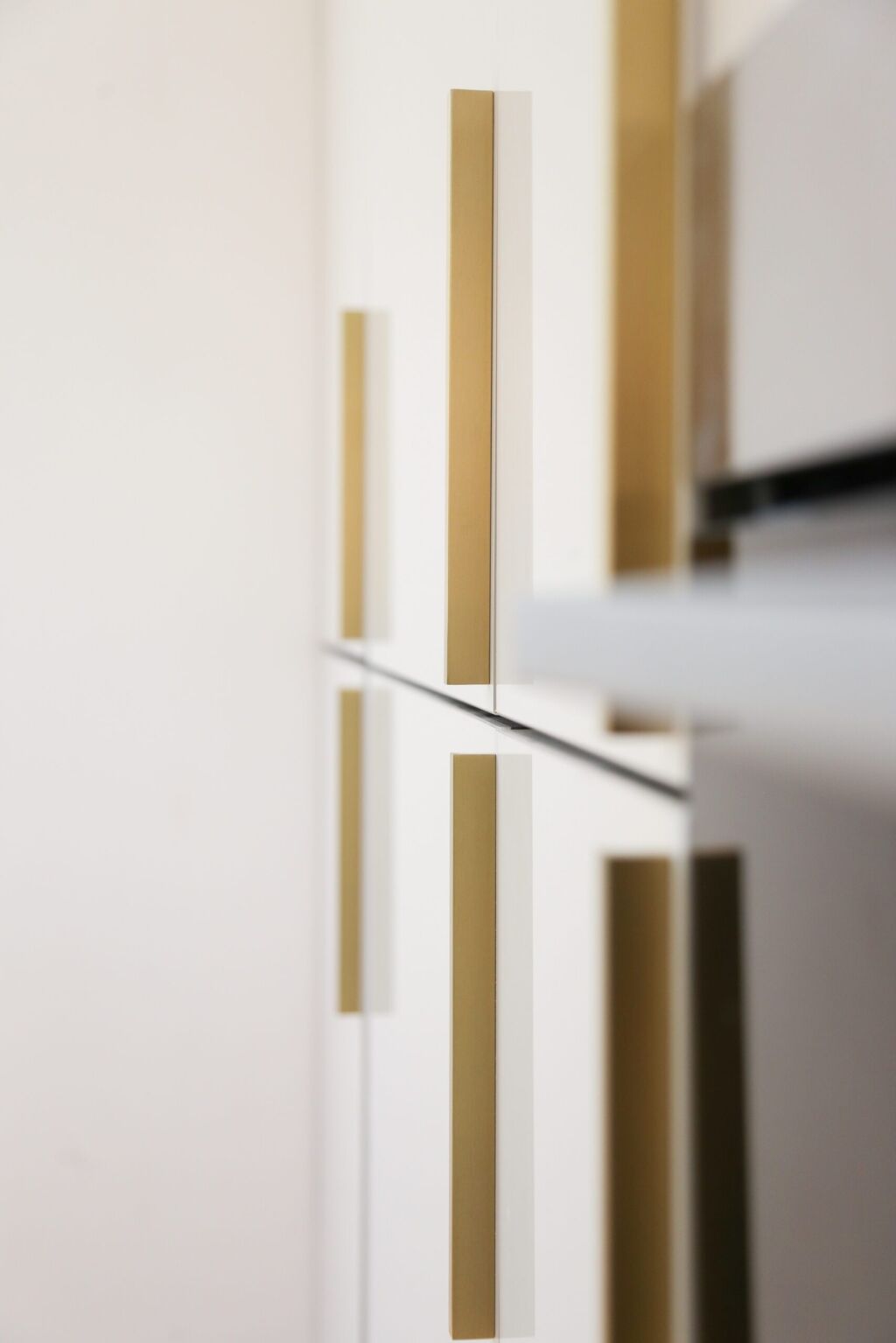 Dover White Quartz worktop edge close-up beside white cabinetry with gold handles