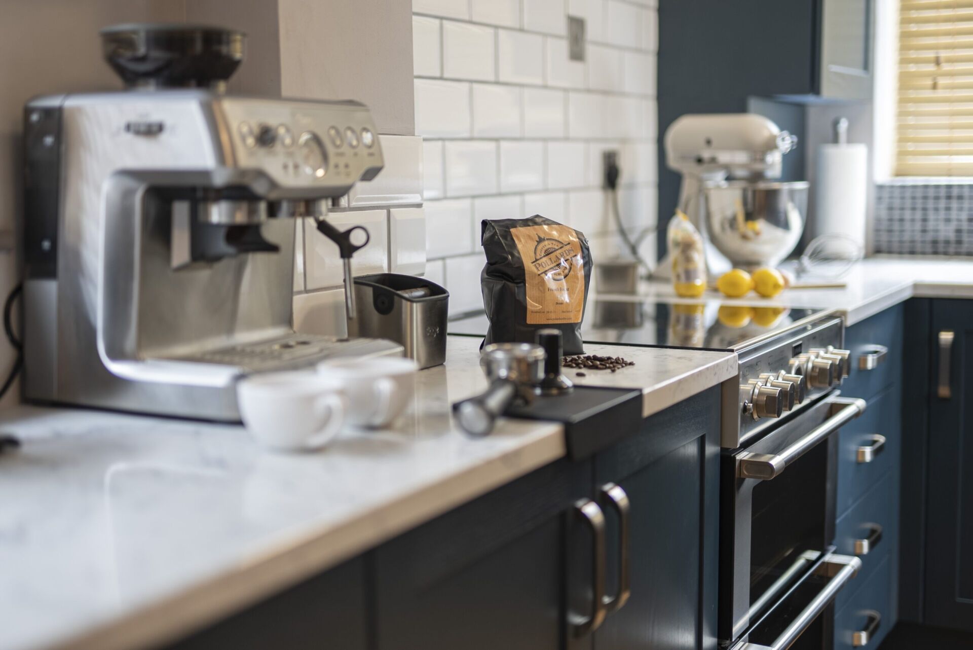 Arabescato Quartz worktop in a dark kitchen run showing grey veining beside small appliances and coffee items