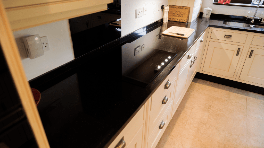 Angled view along a Star Galaxy Granite worktop run showing the polished black surface with sparkling flecks and clean edge detail above light cabinetry.
