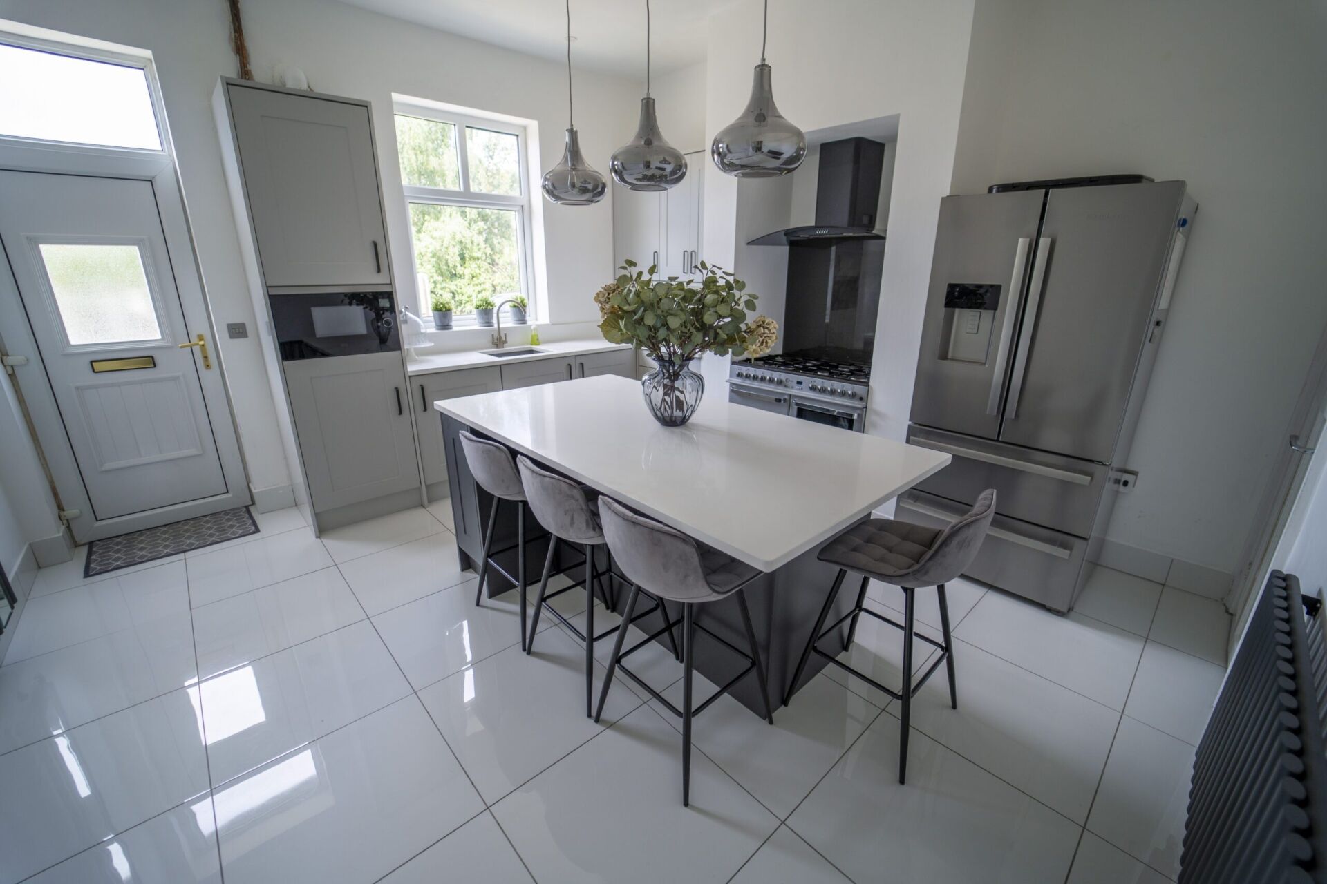 Modern kitchen with a Classic White Quartz island worktop and seating, showing a smooth white surface finish