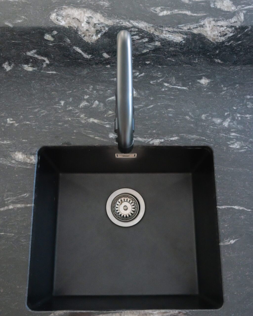 Overhead view of an undermount sink set into Cosmic Black Granite, showing the polished Granite surface and tap positioned above the bowl.
