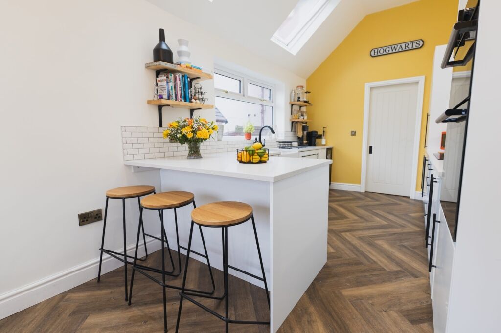 Ice White Quartz breakfast bar island with bar stools in a bright kitchen, showing a smooth white surface finish