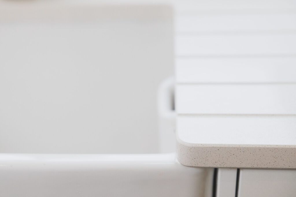 Close-up of Ice White Quartz worktop edge beside a sink, showing a smooth rounded corner and bright finish