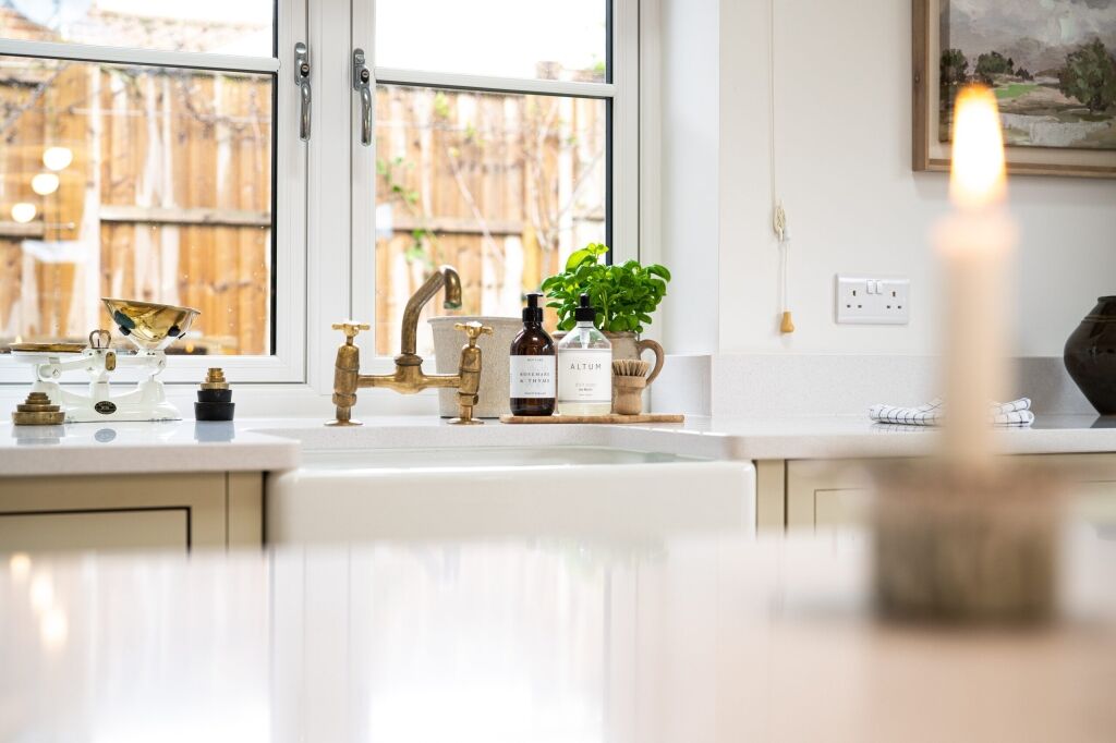 Wide kitchen view with Ice White Quartz worktops around the sink area, brass tap and drainer grooves visible