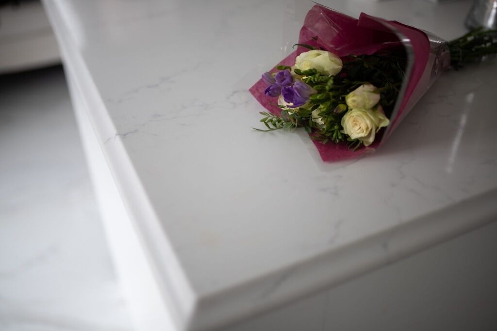 Statuario Bianco Porcelain worktop edge with subtle veining and flowers styled on the surface