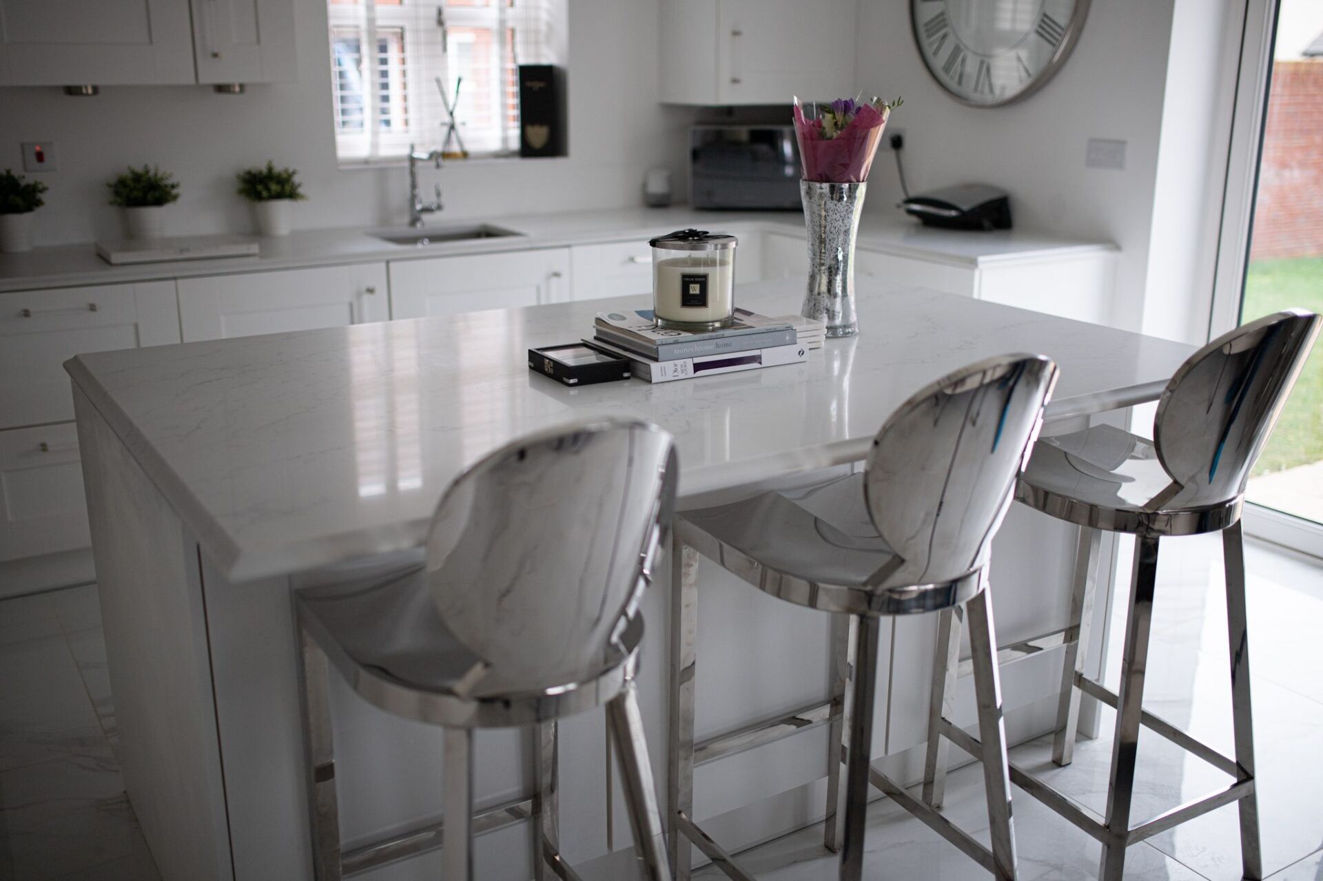 Modern kitchen featuring Statuario Bianco Porcelain island with bar stools and bright white cabinetry