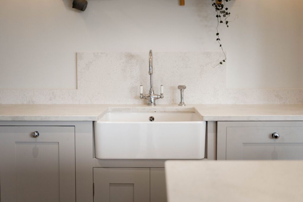White Concrete Quartz worktop behind a farmhouse sink showing soft concrete-effect pattern and clean wall line