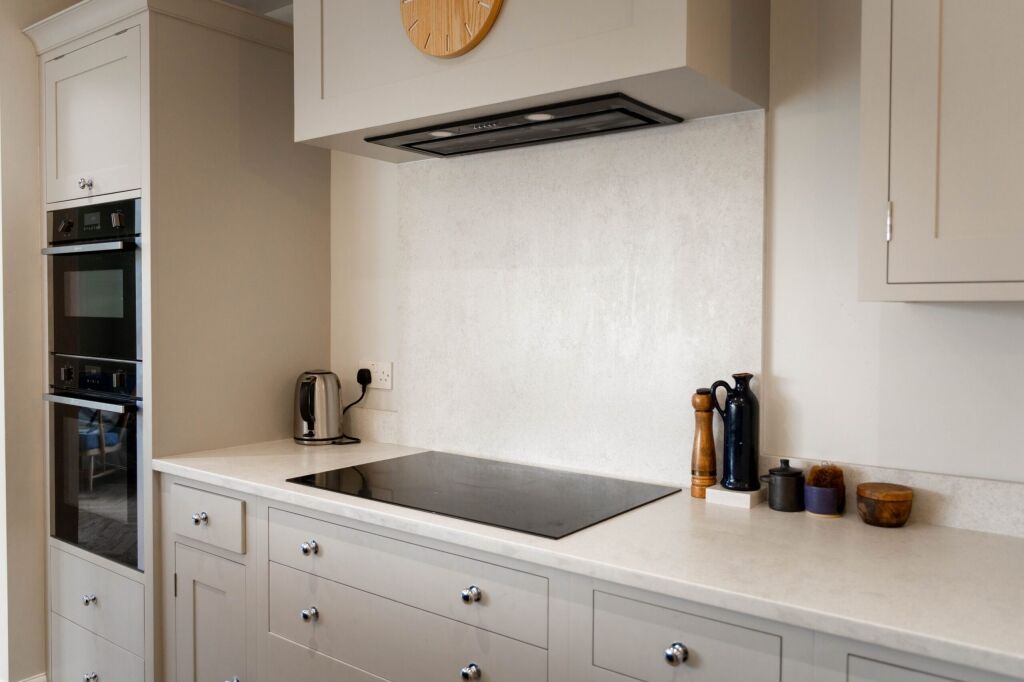 White Concrete Quartz worktop and splashback behind an induction hob with pale concrete-effect mottling