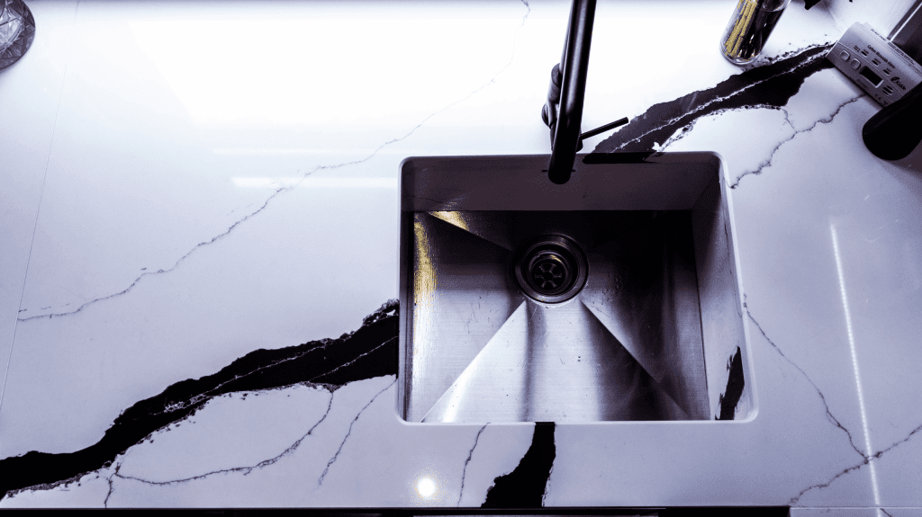 Black Calacatta Quartz worktop with inset sink shown in close-up with bold veining and polished white surface
