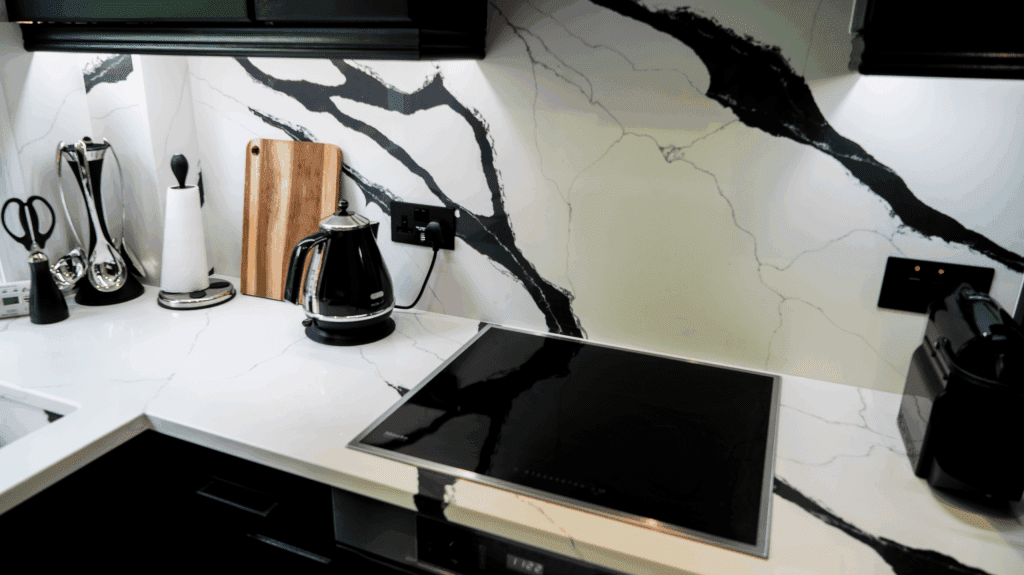 Black Calacatta Quartz worktop and splashback with bold black veining behind an induction hob in a modern kitchen