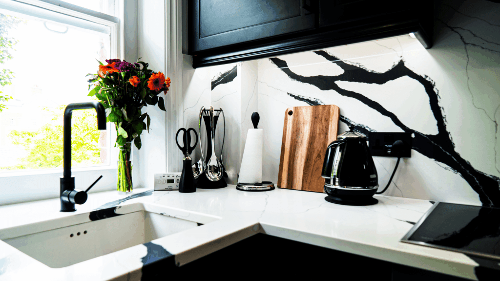 Black Calacatta Quartz corner worktop with matching splashback showing bold veining behind kitchen appliances