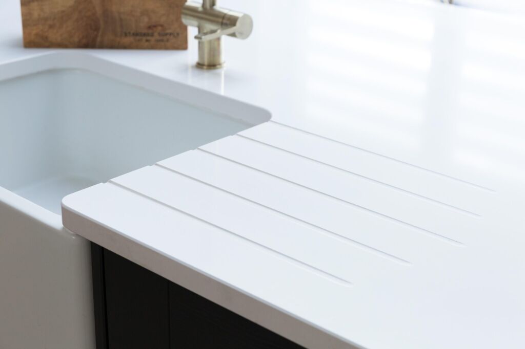 Blanco Zeus Quartz worktop with integrated drainer grooves beside an undermount sink and brass tap