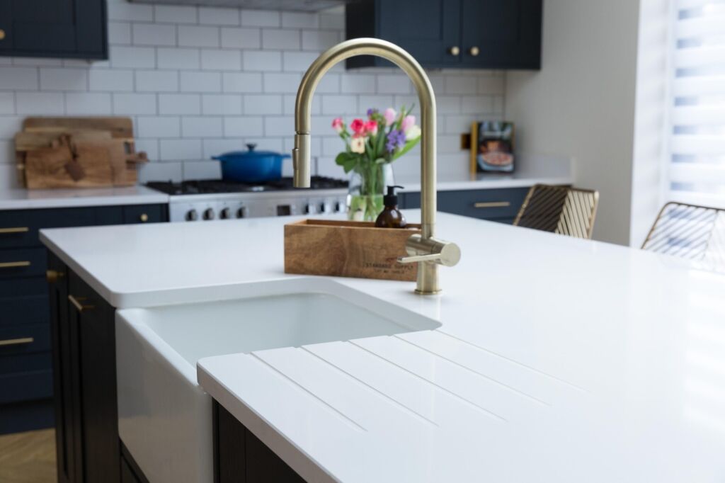 Blanco Zeus Quartz worktop with integrated drainer grooves and undermount sink beside a brass tap
