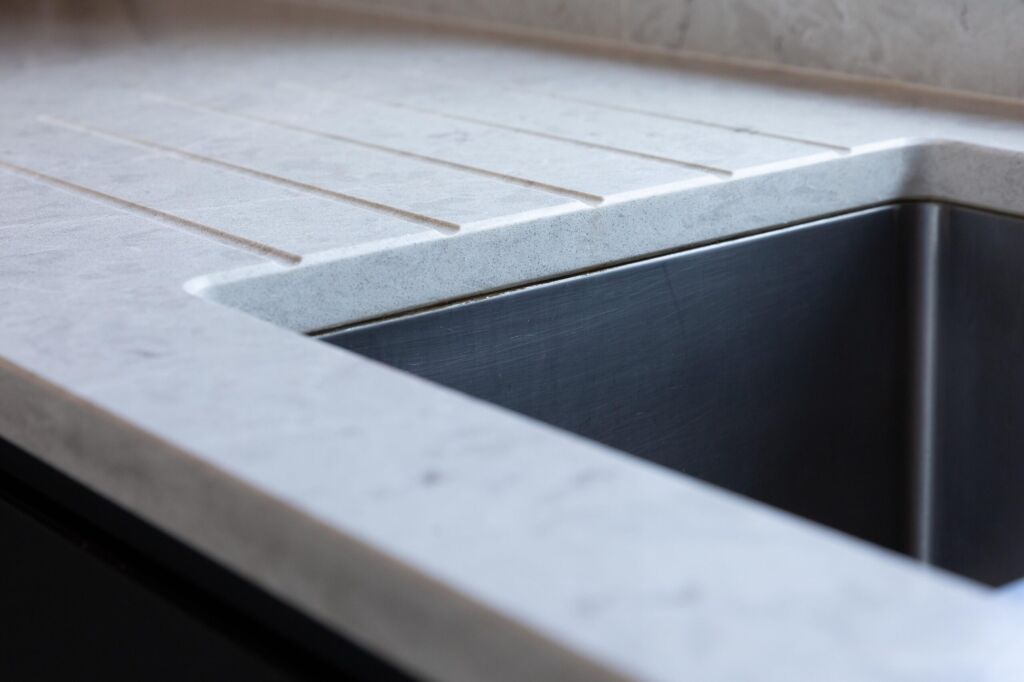 Grey Drift Quartz worktop with integrated drainer grooves and inset sink cut-out shown in close-up