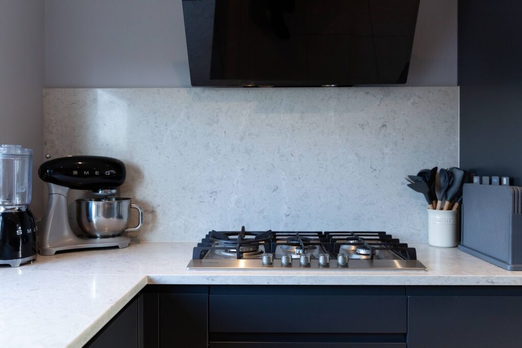 Grey Drift Quartz worktop behind a gas hob showing pale grey stone-effect movement and clean cut-out lines