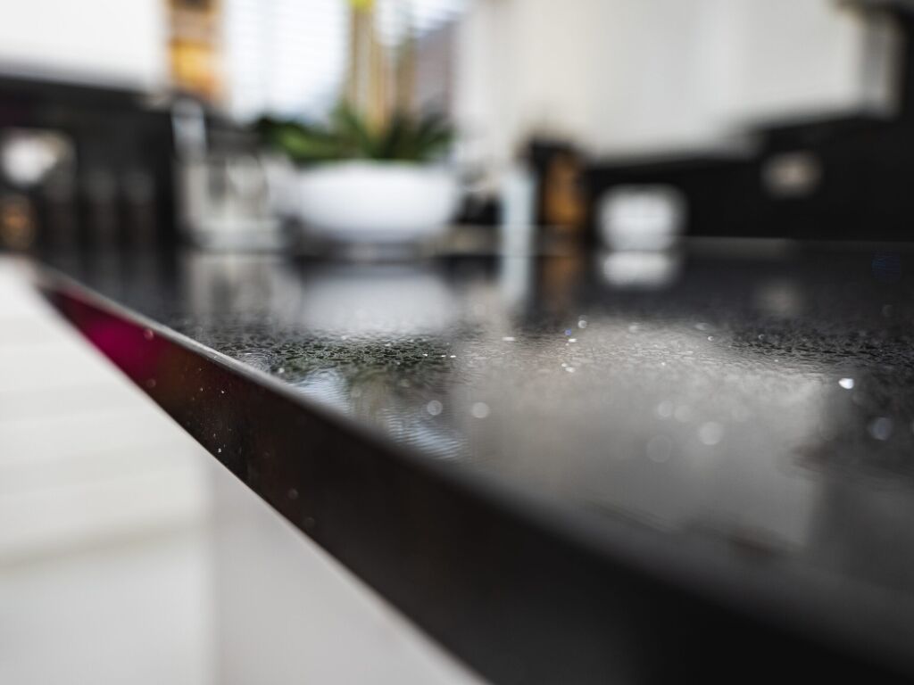 Macro close-up of Black Starlight Quartz worktop showing fine reflective speckles on a polished black surface