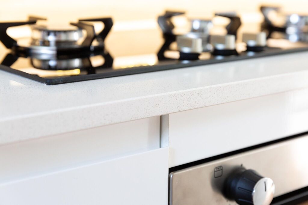 Close-up of a gas hob set into an Ice White Quartz worktop with the front edge and drawer details visible