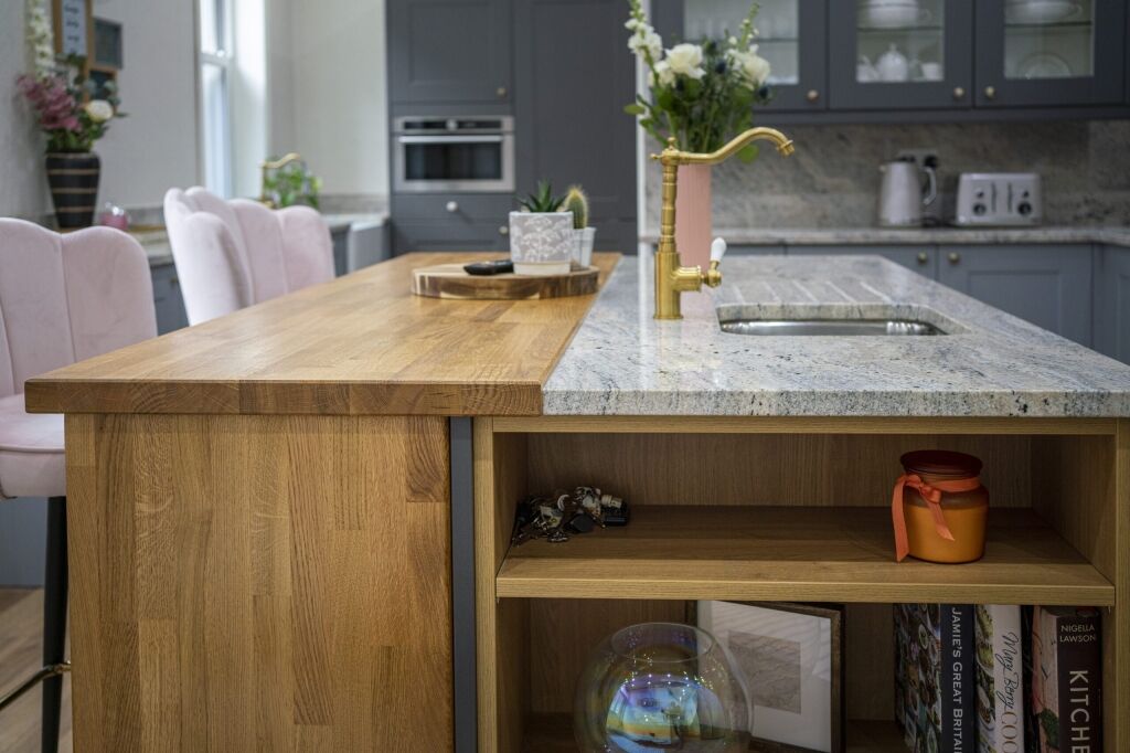 Island end view showing an Ivory Fantasy Granite worktop with inset sink, styled with flowers and accessories above open shelving.