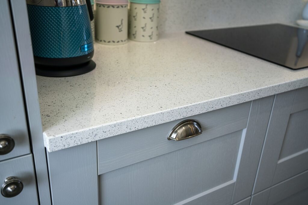 White Starlight Quartz worktop corner above grey cabinetry with modern hardware