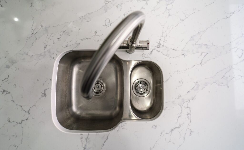 Close up of chrome tap fitted into White Calacatta Quartz worktop with grey veining