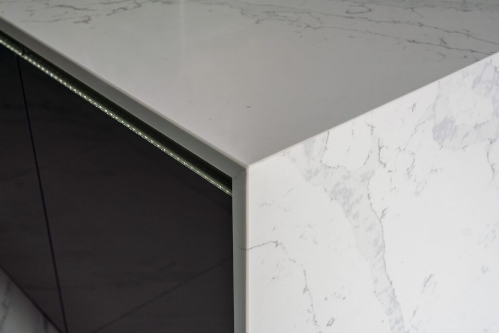 White Calacatta Quartz waterfall island corner showing polished edge and grey veining