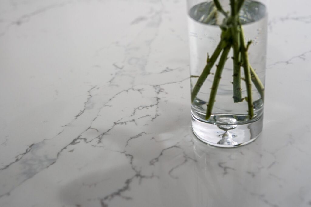 Close up of White Calacatta Quartz worktop surface with grey veining and vase of flowers