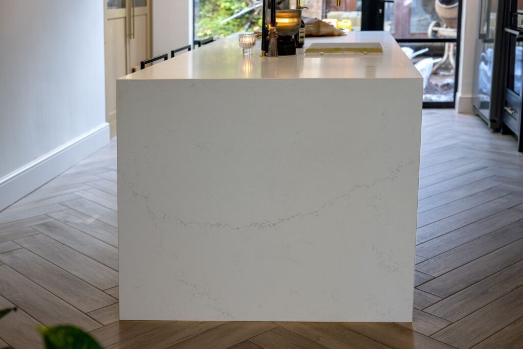 End view of an Olympus White Quartz kitchen island showing the smooth white finish and subtle veining