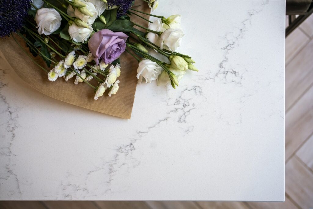 Olympus White Quartz worktop close-up with subtle grey veining beside flowers and kitchen styling