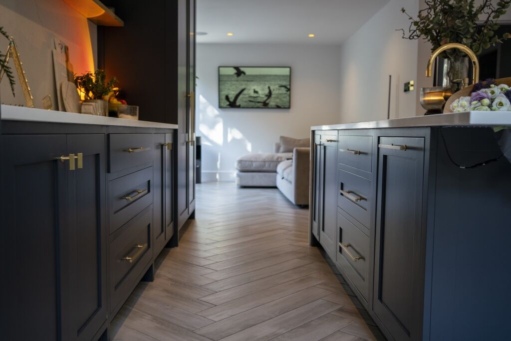 Long kitchen view with an Olympus White Quartz island worktop running through the centre of dark cabinetry