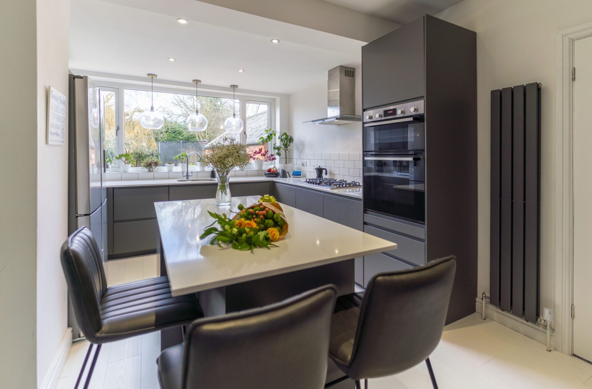Blanco Zeus Quartz island worktop with bright white surface and seating in a modern kitchen with dark cabinetry