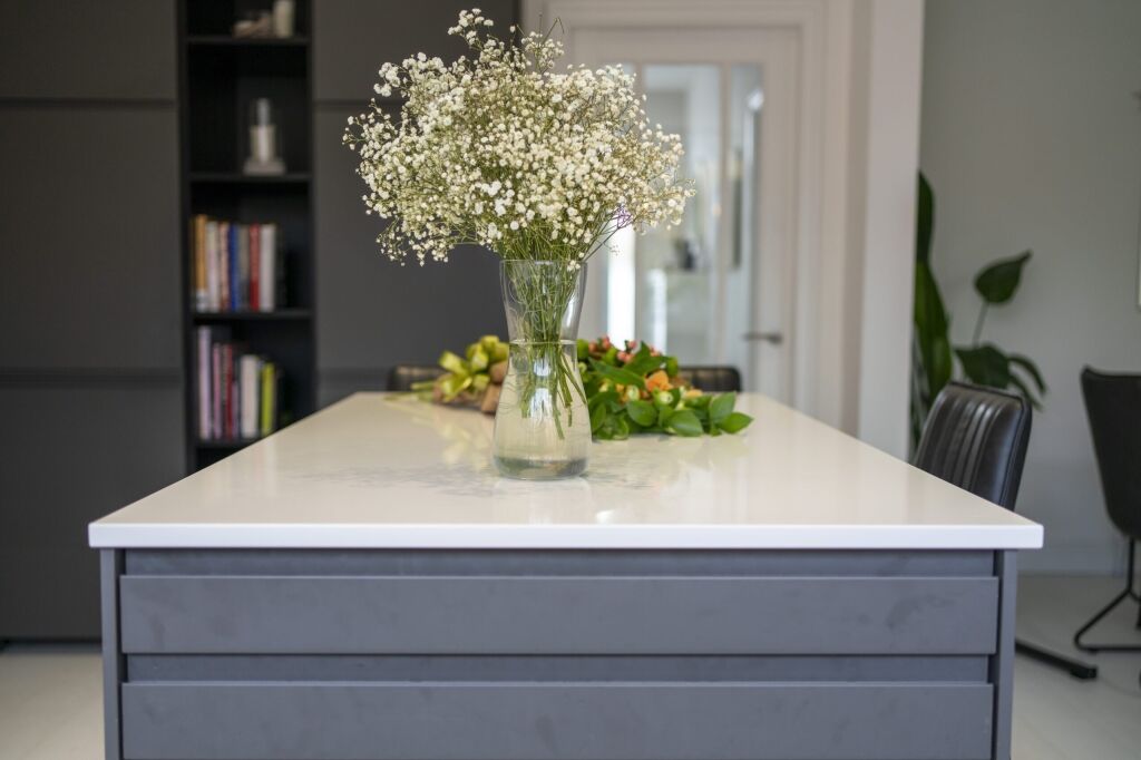 Blanco Zeus Quartz island worktop with bright white surface shown end-on with flowers on the countertop