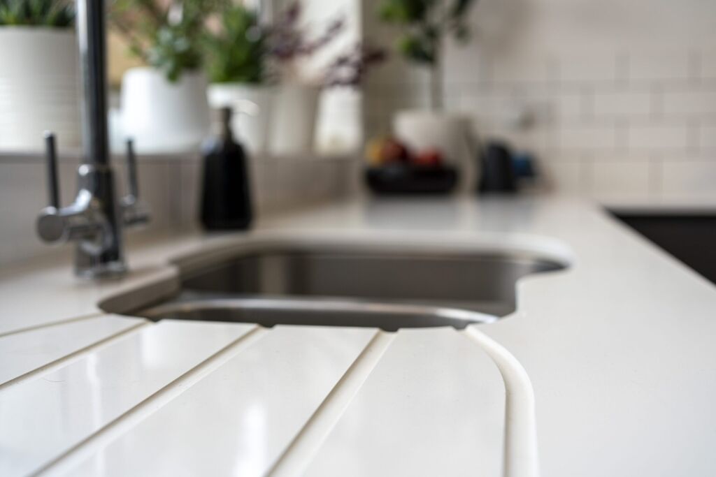 Blanco Zeus Quartz worktop close-up with integrated drainer grooves beside an undermount sink on a bright white surface