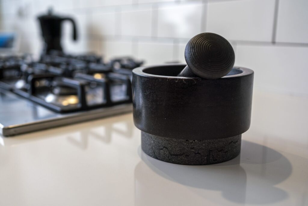 Blanco Zeus Quartz worktop close-up with a black stone mortar and pestle on a bright white surface near the hob