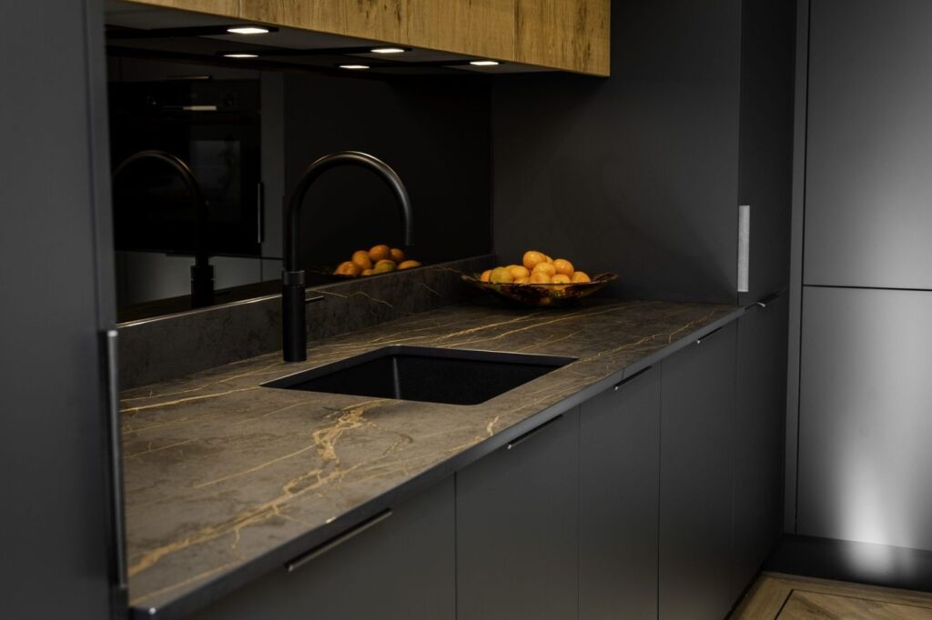 Laurent Porcelain worktop with gold veining installed around an undermount sink and black tap, with fruit bowl on the surface.