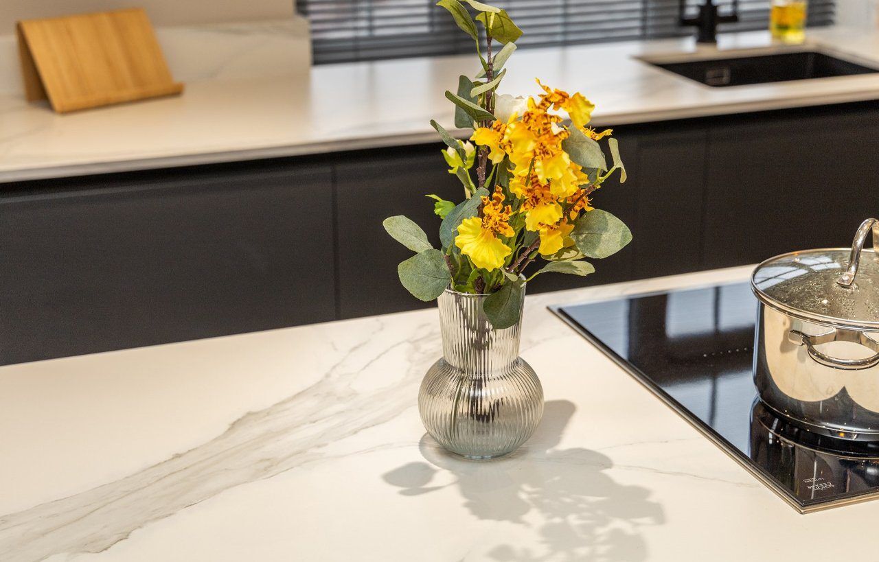 Volakas White Porcelain worktop surface with light grey veining, shown with a vase of flowers on top.