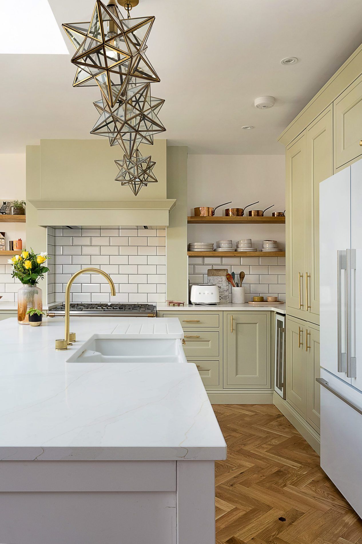 Eternal Calacatta Quartz worktops around sink area in a modern kitchen with gold tap and sage cabinets